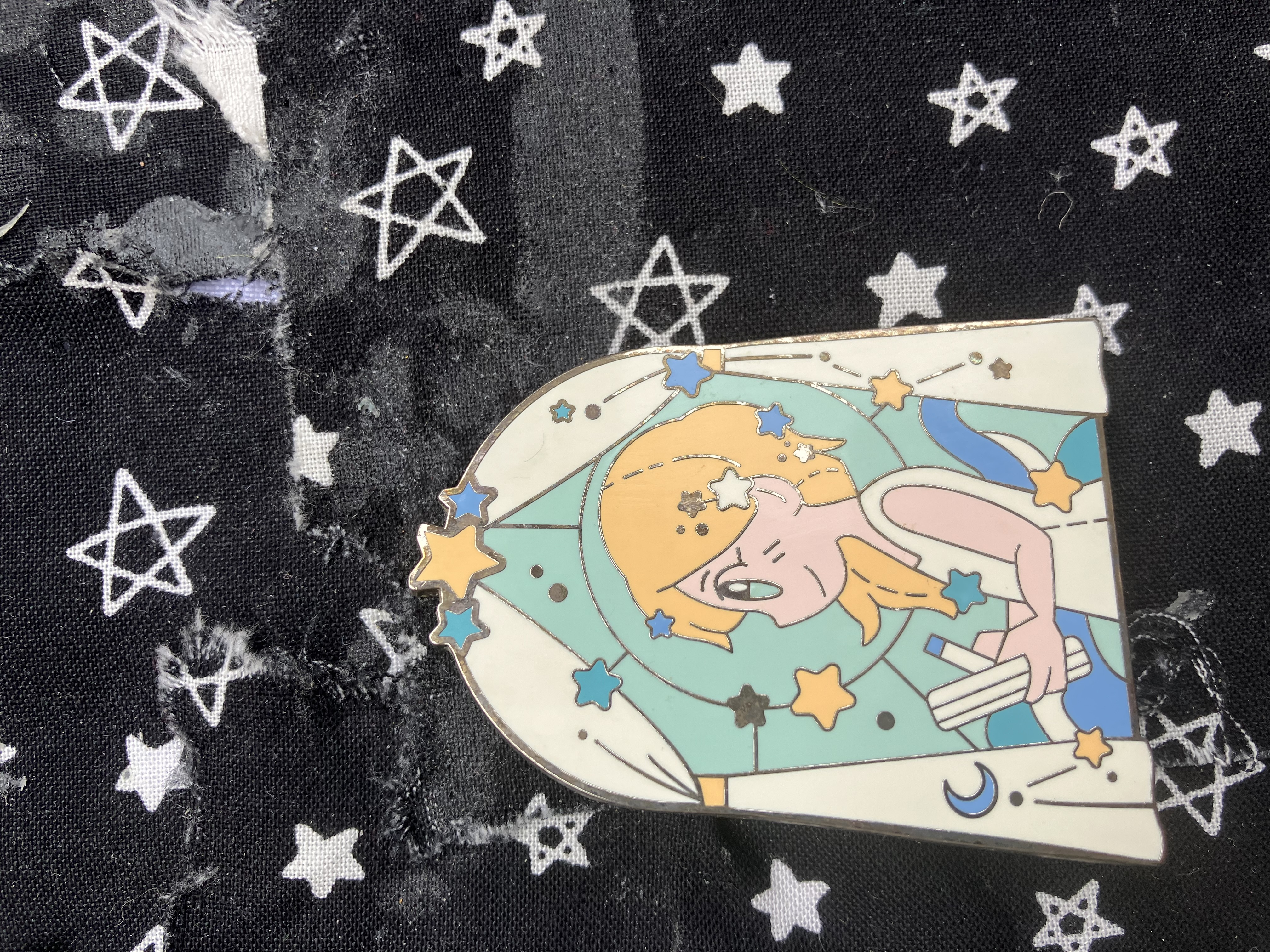Enamel pin in a stained glass style of Kingdom hearts Namine holding a sketchpad and crayon.
